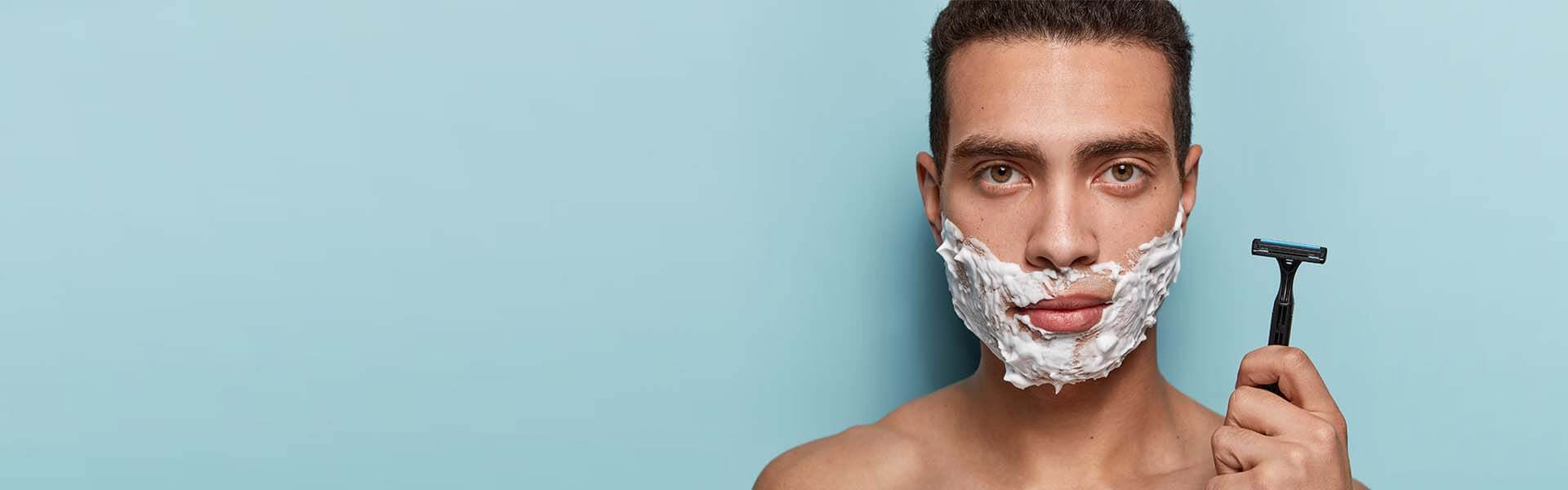 Mann rasiert sein Gesicht sorgfältig mit einem Nassrasierer